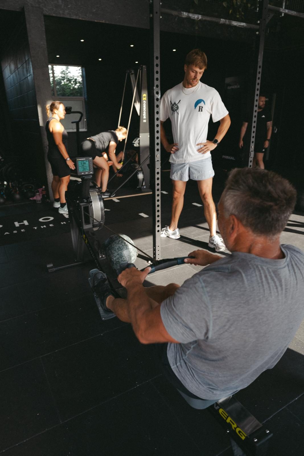 Coach standing over a member on the rower